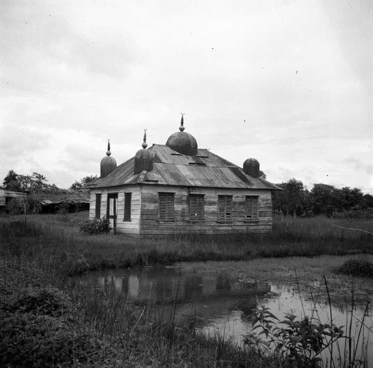 De komst van Brits-Indische contractarbeiders naar Suriname betekende ook de komst van een nieuwe religie naar de kolonie: het Hindoeïsme. Hier staat een Hindoeïstische tempel in een Surinaams veld. (Foto: Willem van de Poll, 1947, nationaal Archief)