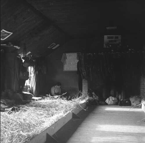 Slaapruimte in de blokhut met in de hoek linksachter een lezende soldaat in hemdsmouwen, zittend in het stro. (Foto: Johan Prinsen, Collectie familie Prinsen, 1939)