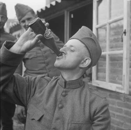 Eén van de soldaten van foto 3 drinkt een flesje chocolademelk, twee anderen kijken glimlachend toe. (Foto: Johan Prinsen, Collectie familie Prinsen, 1939)